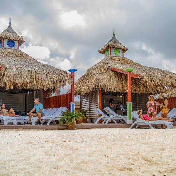 a group of people sitting at a beach umbrella in the sand