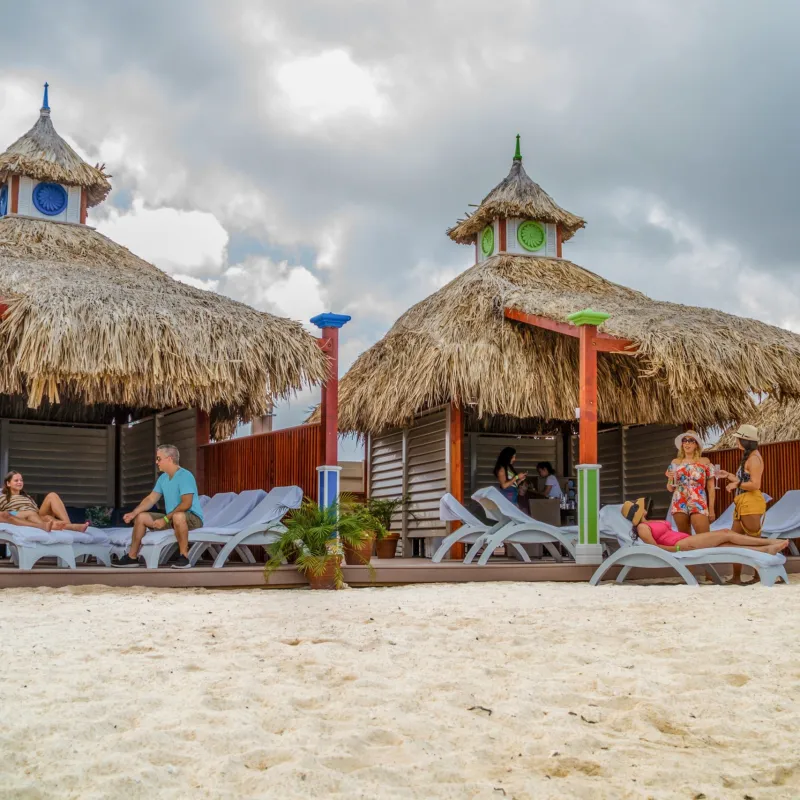 a group of people sitting at a beach umbrella in the sand