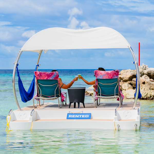 Couple relaxing on rented boat with canopy, holding hands.