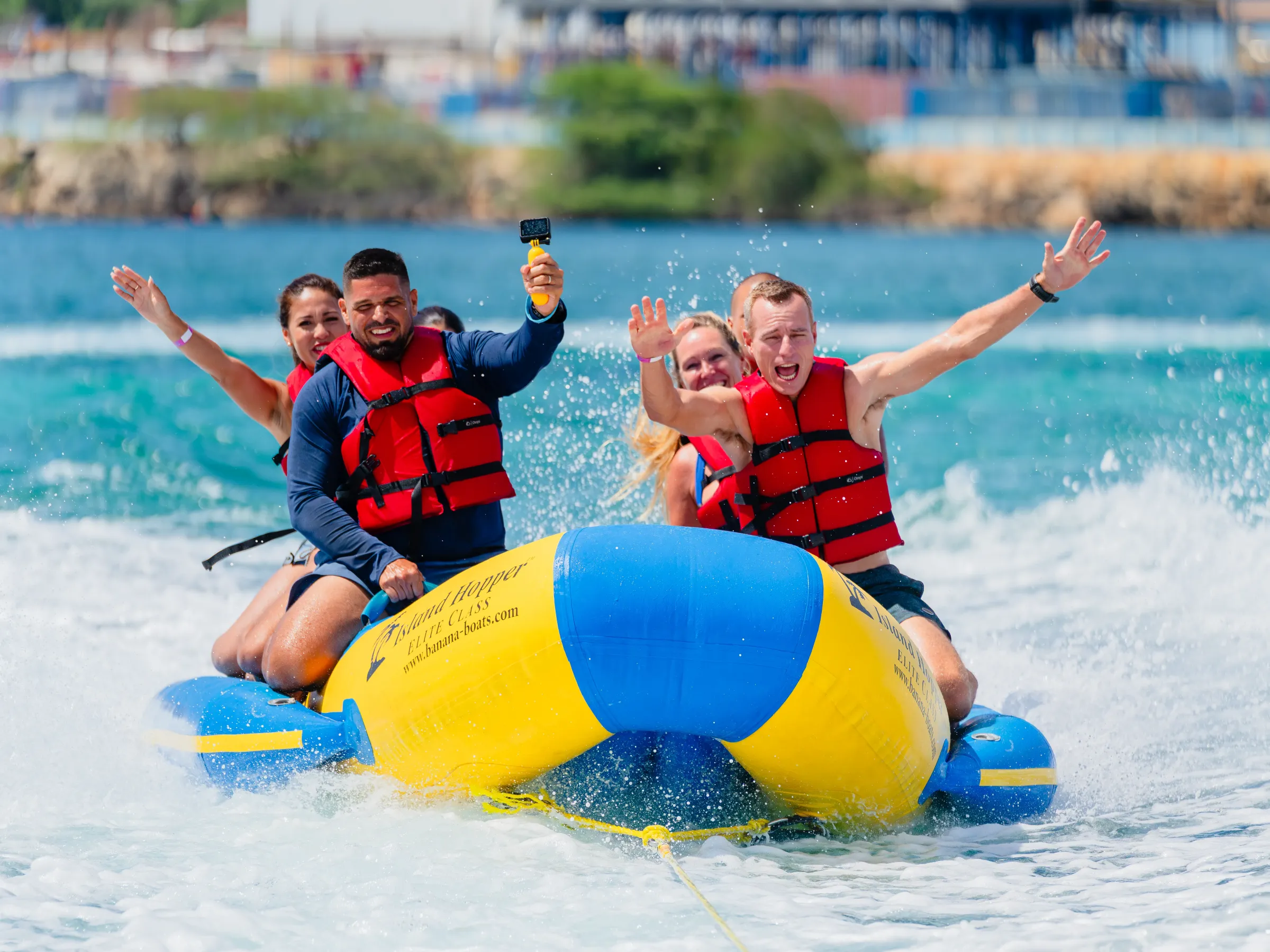 Four people in life vests enjoying a banana boat ride on the ocean.