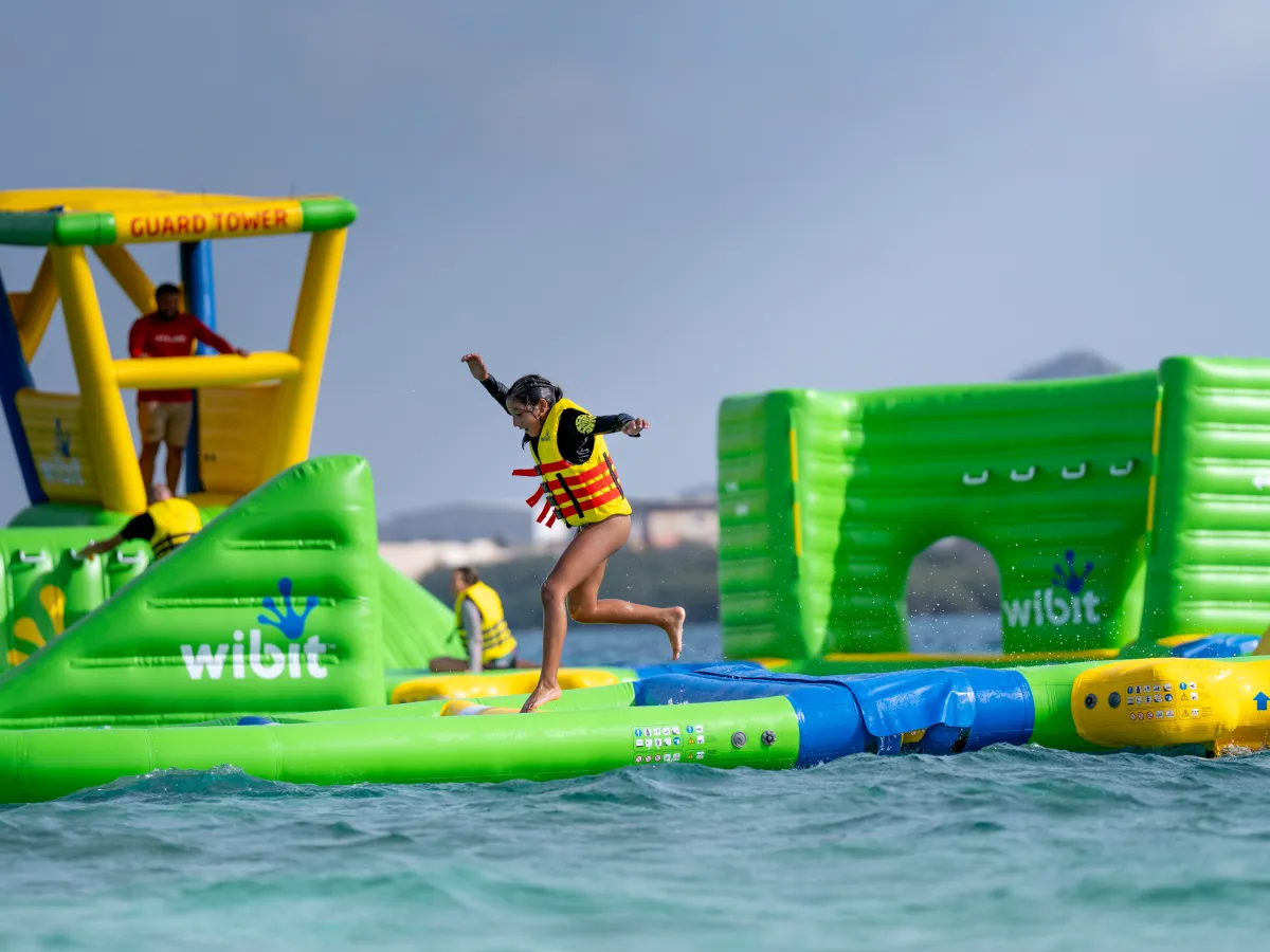 Splash Park Person in a life jacket jumping on floating obstacle course on water.