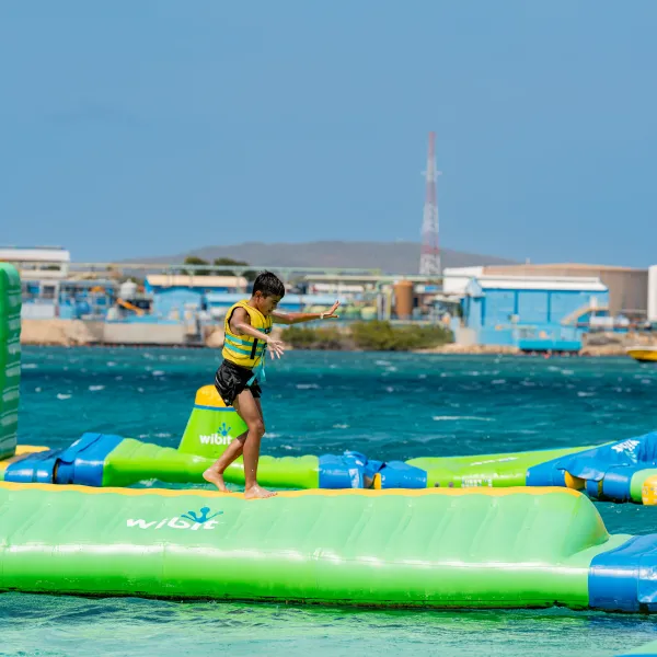 Child balancing on inflatable water park obstacle course.